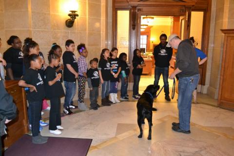 DCI Special Agent Michael Reimer with Yuma, DCIâ€™s arson dog, doing a demonstration outside of the Attorney Generalâ€™s Capitol office